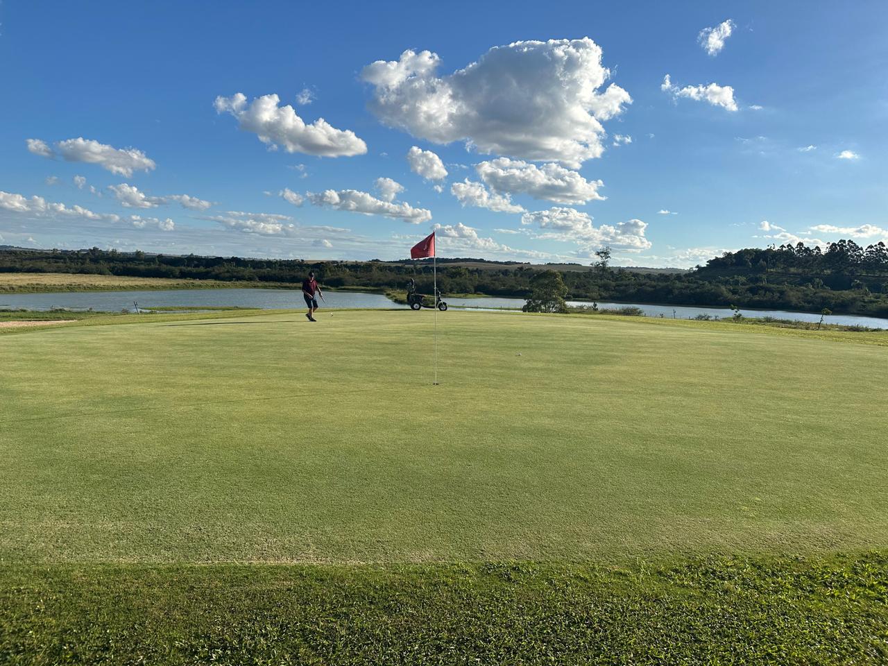 Putting green com golfista ao fundo