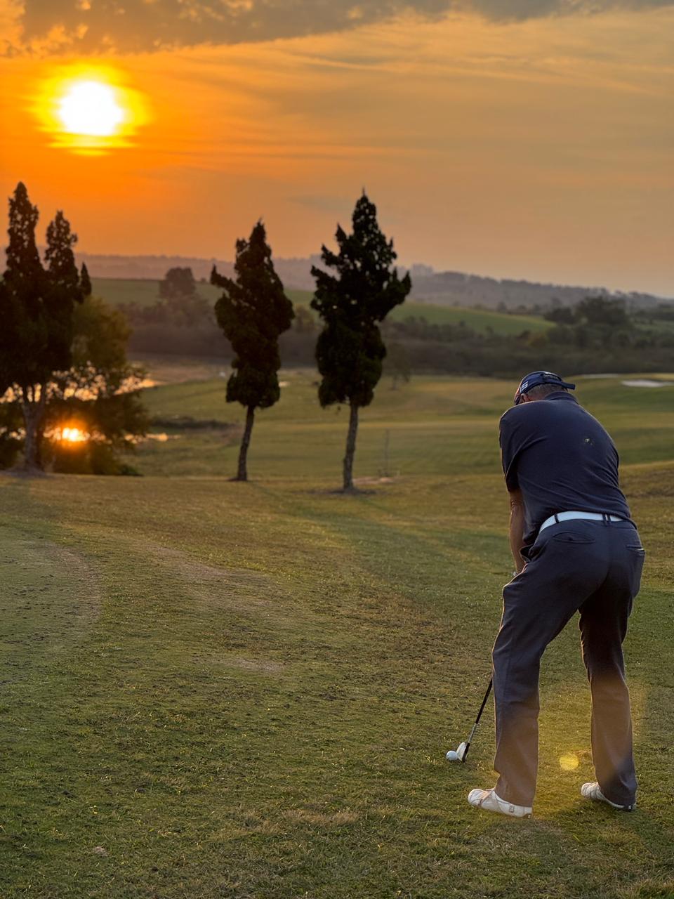 Golfista no tee ao pôr do sol